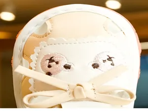 Detail of baby walking sandals with cute bear embroidery and cream bow decoration