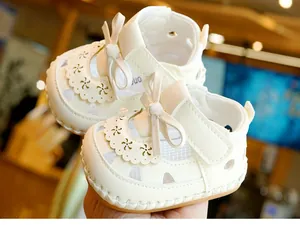 Detail of white infant sandal with bow, cutout petal edges and soft anti-slip sole