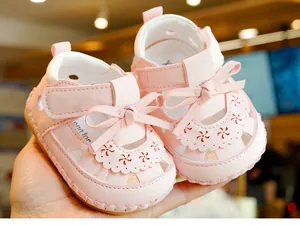 Detail of pink baby sandal showing cutout floral patterns and 3D bow decoration