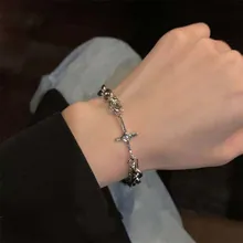 Detailed view of silver cuban link bracelet with gothic cross and flame heart charms