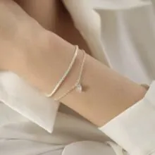 Detail of silver double-layered bracelet with heart pendant on model's wrist