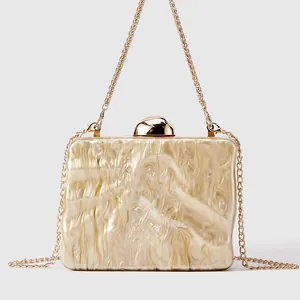 Close-up of marble texture acrylic evening bag with gold wavy sides and chain strap
