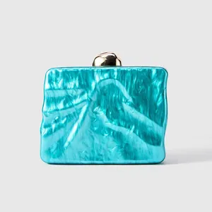 Detail of teal marble acrylic evening clutch with wavy texture and gold metal clasp