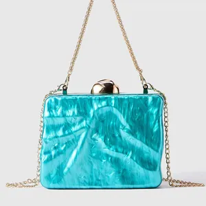 Macro view of turquoise marble acrylic clutch with gold hardware and chain strap