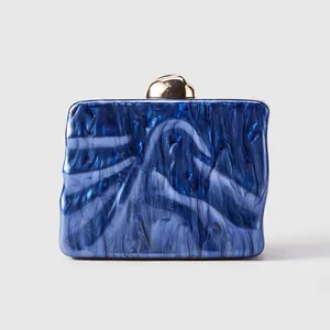 Detail of blue marble acrylic evening bag featuring wavy edges and golden sphere clasp