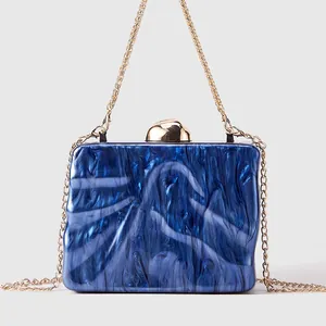 Detail of blue marble acrylic clutch showing gold metal clasp and chain strap