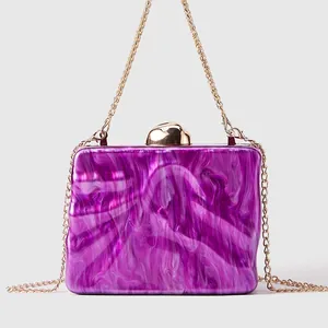 Detail of purple marble acrylic clutch with elegant gold metal clasp and chain strap