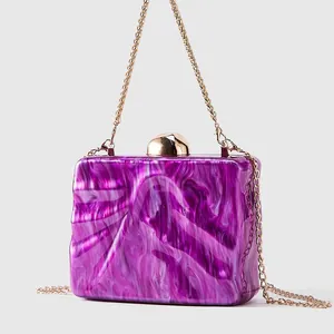 Macro view of purple marble texture acrylic evening bag with gold sphere clasp and chain