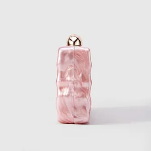 Detailed side view of pink acrylic clutch with wavy texture and gold sphere clasp