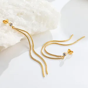 Detail view of gold snake chain long tassel earrings with sparkling clear crystal