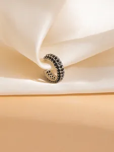 Macro shot of silver ear cuff with three rows of pavé-set black zircon stones on silk