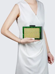 Macro detail of green marble acrylic frame and natural rattan woven panel on clutch