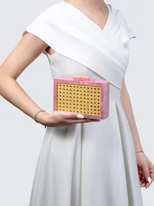 Detail of a pink marble acrylic clutch bag with woven straw panel held by model