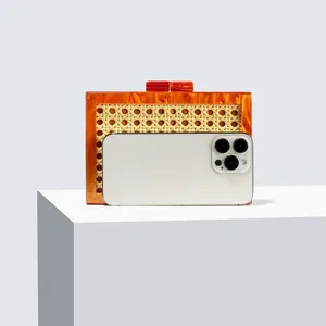 Detail of evening clutch with orange marble resin frame and woven rattan paneling