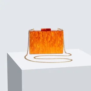 Detailed macro view of orange marble acrylic evening clutch with gold chain strap
