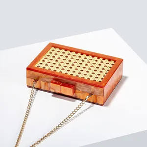 Detail of green rattan woven acrylic clutch bag with marble texture and gold chain strap