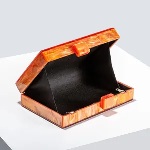 Macro detail of amber marble acrylic clutch bag with black lining and metal hinges
