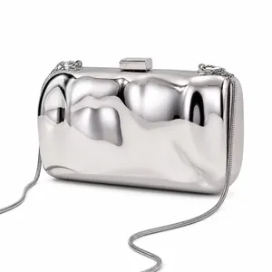 Close-up of irregular liquid metal texture and silver snake chain on evening clutch bag