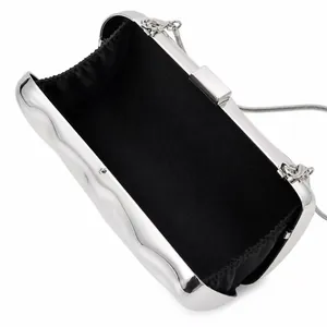 Macro view of silver evening bag with wavy metal texture and black fabric lining