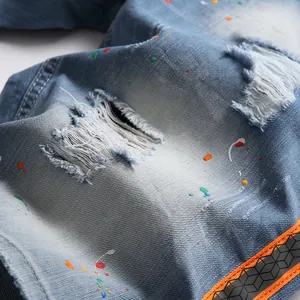 Light blue wash denim shorts with distressed rips and multi-color paint splatter design