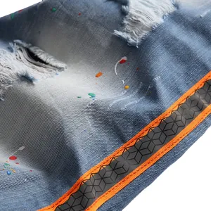 Distressed blue denim shorts with colorful paint splatter and orange 3D geometric side tape