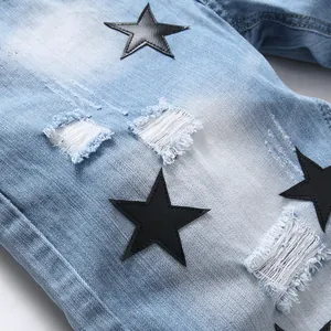Men's slim-fit ripped denim shorts featuring black leather star patches and distressed details