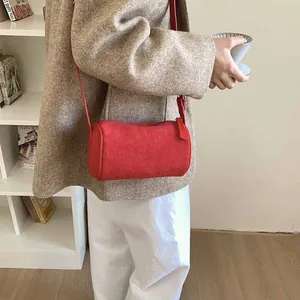 Minimalist red cylindrical frosted suede shoulder bag shown as a side view on a model