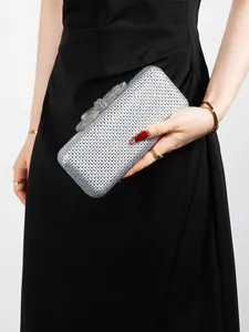 Detailed macro view of a silver rhinestone clutch bag with a sparkling crystal bow clasp