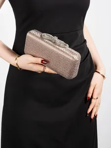 Detailed view of luxury rhinestone evening clutch with bow clasp held by a model