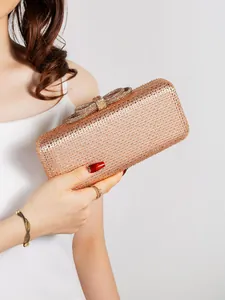 Detail of champagne gold evening clutch featuring pavé rhinestones and bow clasp