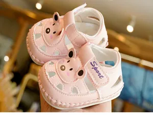 Detailed close-up of pink baby sandals with cute bear decoration and hollow breathable design