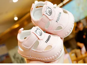 Détail d'une sandale rose pour bébé avec motif d'ours, velcro et semelle antidérapante