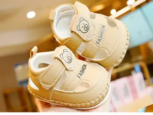 Gros plan de sandales bébé en cuir avec icône ours mignonne et détail velcro