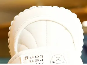 Macro shot of white baby shoe featuring shell quilting and pearl wave edge detailing