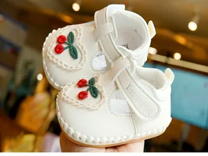 Détail de chaussures bébé avec broderie cerise rouge et bordure en dentelle