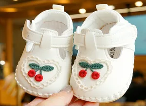 Détail de chaussures de marche souples pour bébé blanches avec broderie de cerises