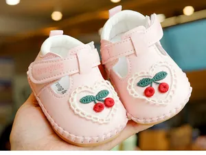 Gros plan de chaussures bébé roses avec broderie cerise, dentelle cœur et scratch réglable