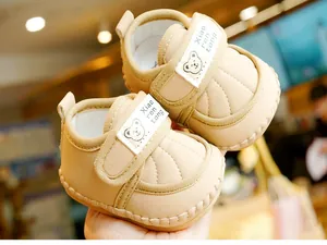 Detail of baby walking shoes with beige quilted faux leather and cute bear velcro strap