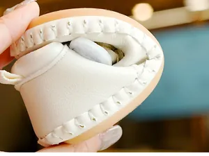 Detail showing the high flexibility and softness of white baby shoes with brown rubber soles