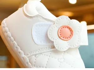 Detail of baby walker shoes featuring beige quilted leather and decorative floral velcro strap