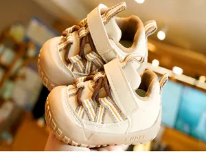 Detail view of beige baby walking shoes with hook-and-loop closure and embossed sole text