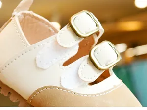 Detail of beige toddler leather shoes with double straps and vintage buckles
