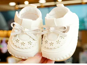 Detail of white leather baby princess shoes with hollow flower patterns and bow accents