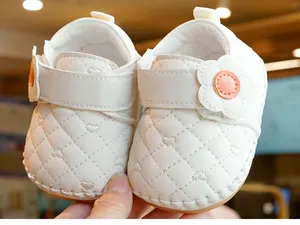 Close-up of baby walking shoes with heart quilting, flower detail and soft rubber sole