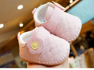 Close-up of pink baby shoes featuring heart stitching and decorative flowers