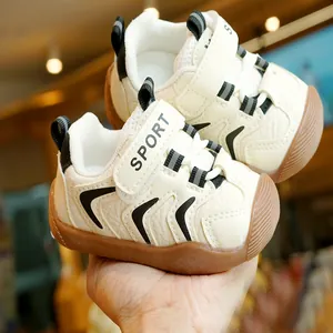 Beige infant walking shoes with black stripes and brown non-slip rubber soles