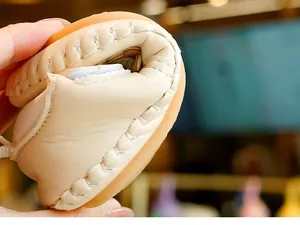 Close-up of flexible cream baby shoe with non-slip rubber sole showing 180-degree bend