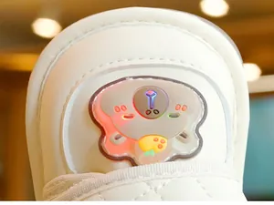 Dettaglio macro di scarpe per neonati color crema con luci LED colorate e decoro orso