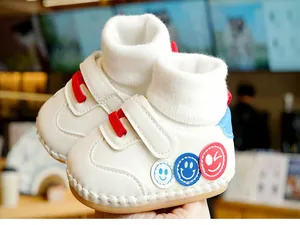 Gros plan de chaussures bébé blanches à semelles souples, patchs smiley et col tricot