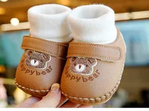 Details von braunen Babyschuhen mit Bärenstickerei und weichem Strickbündchen am Knöchel